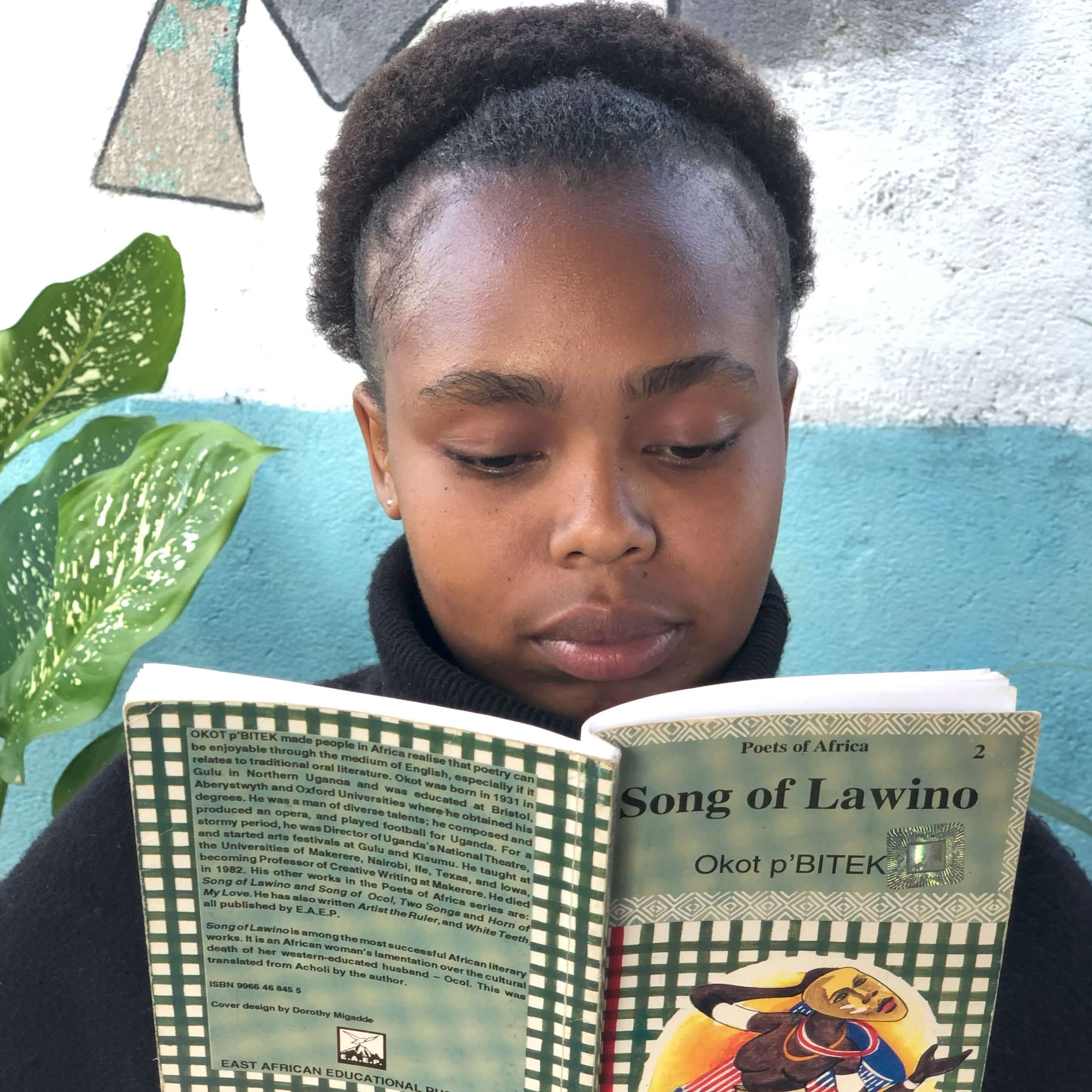 A girl reads a book Song of Lawino at the Elimu Yetu Reading Lounge